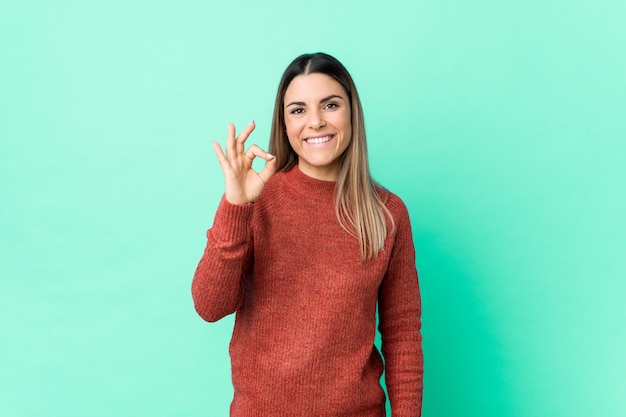 Young woman cheerful and confident showing ok gesture.