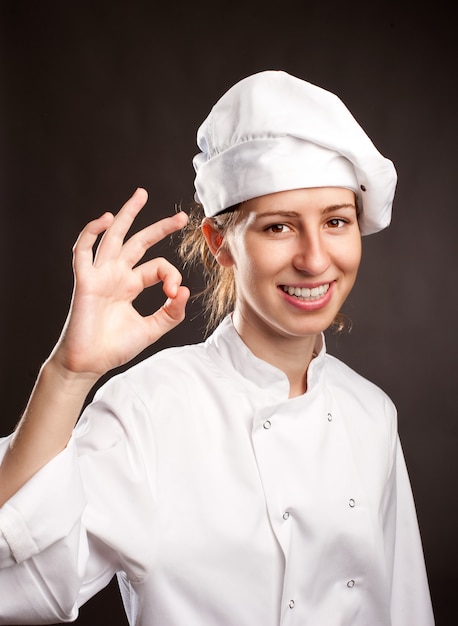 young woman chef giving ok on gray 