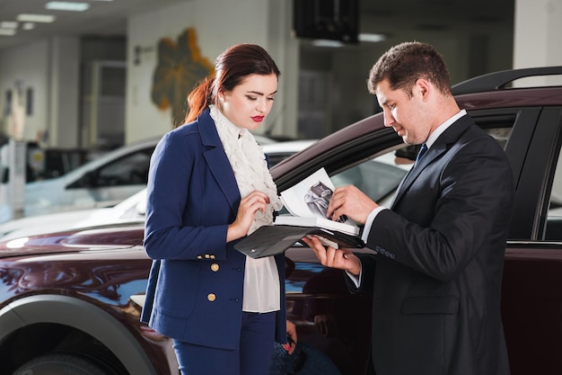 Young woman chooses an expensive SUV at the car dealership