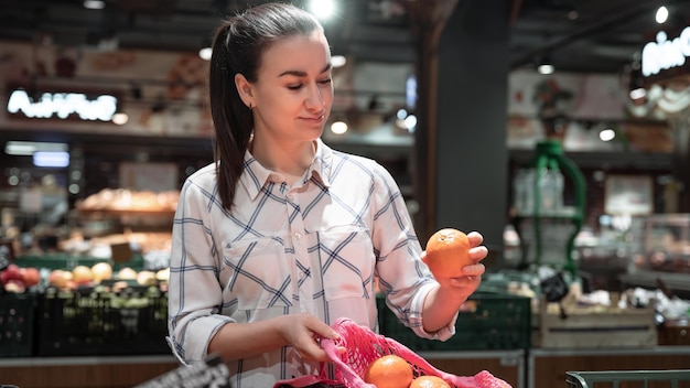 A young woman chooses fruits in a supermarket