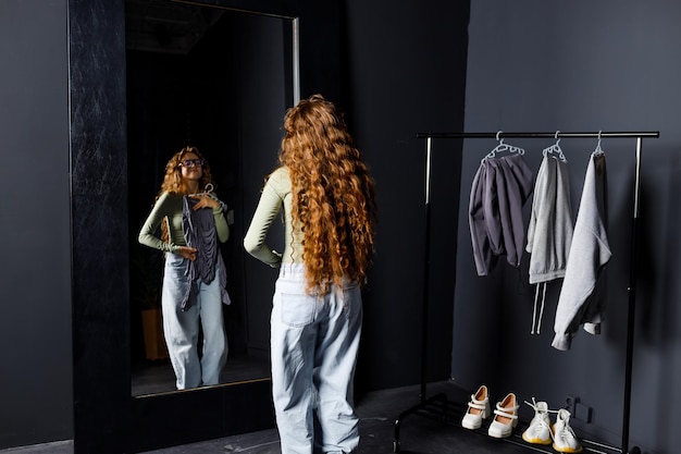 Photo young woman choosing clothes at fitting room shopping concept