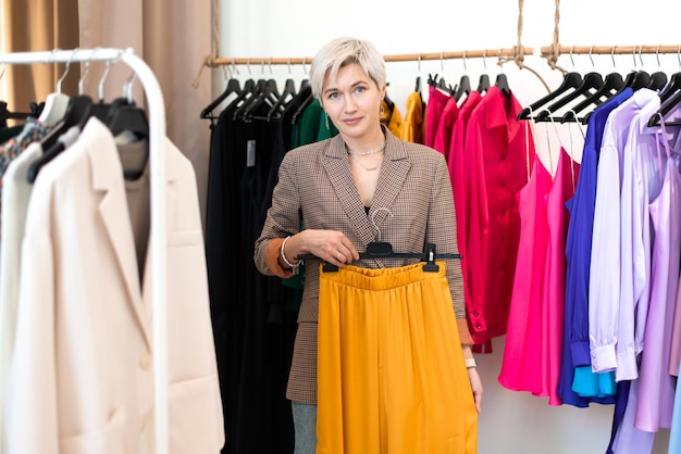 Young woman choosing clothes at store looking at camera