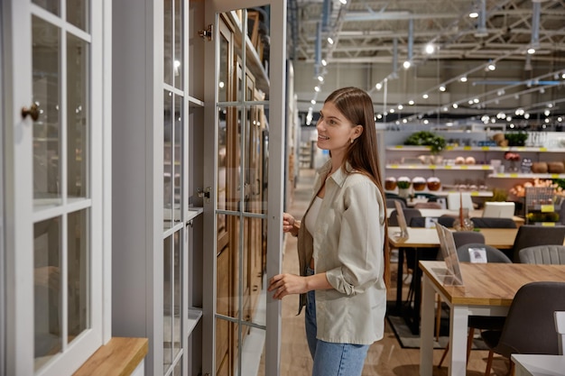 Young woman choosing cupboard at store market