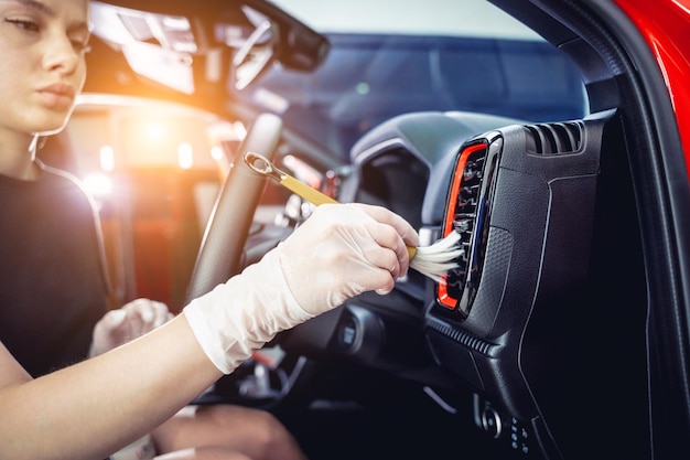 Young woman cleaning the car interior using a special brush with foam