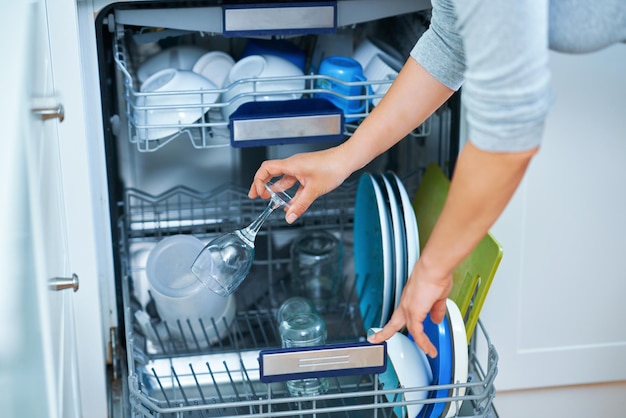 Young woman cleaning dishwasher in the kitchen