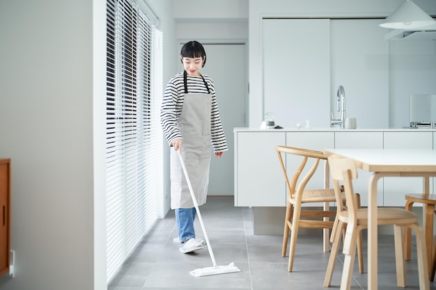 Young woman cleaning the floor in the room