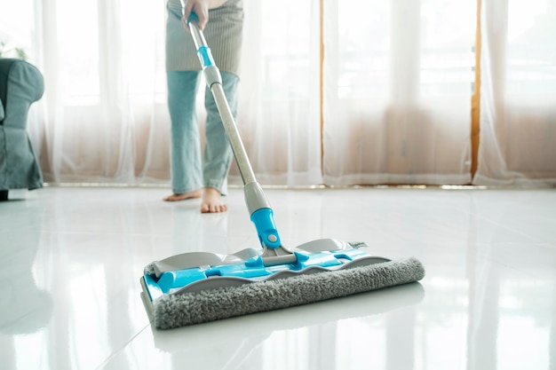 Young woman cleaning floor using mop at home