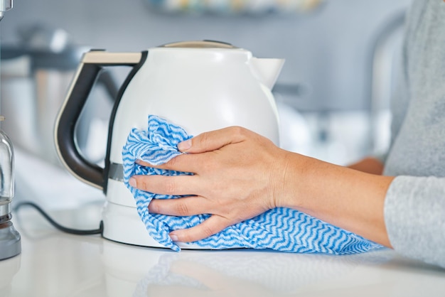 Young woman cleaning kettle in the kitchen