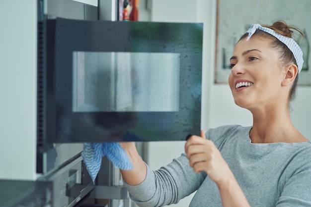 Young woman cleaning oven in the kitchen