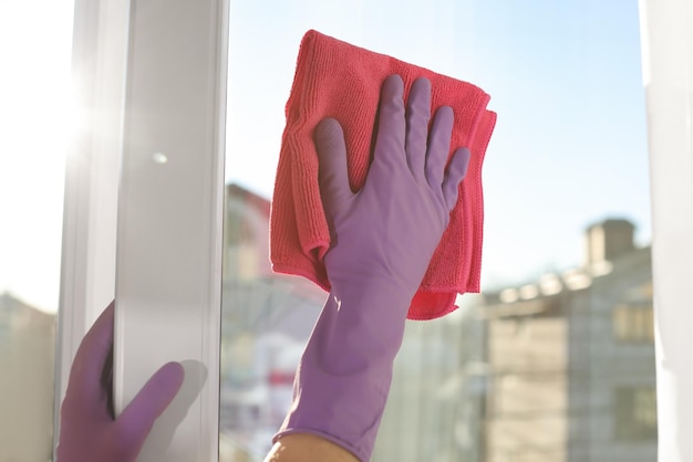 Young woman cleaning window glass with rag at home closeup