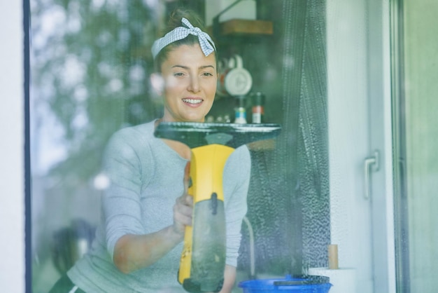 Young woman cleaning window int he kitchen