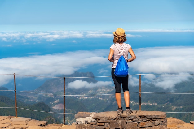 A young woman above the clouds at Miradouro do Juncal on Pico do Arieiro Madeira Portugal