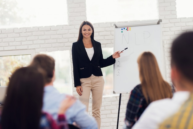 Young woman coacher is conducting seminar.