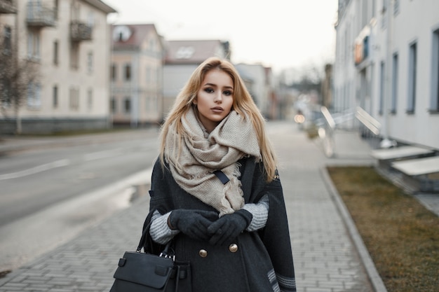 Young woman in a coat with a scarf in the city