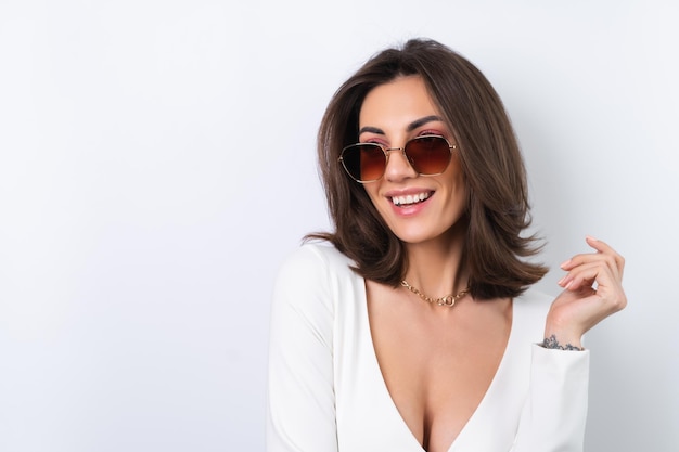 Young woman in a cocktail dress gold chain bright spring pink makeup on a white background In fashionable stylish sunglasses