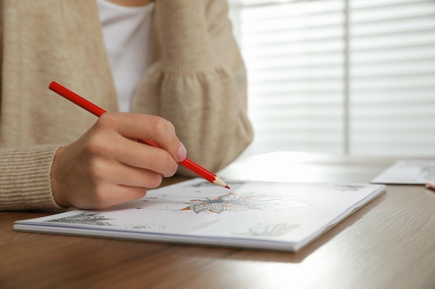 Young woman coloring antistress page at table indoors closeup Space for text