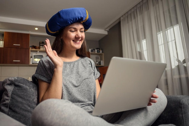 Young woman communicates in social networks with laptop, girl sitting at home in chair with laptop, girl with turban on her head, chat with friends abroad