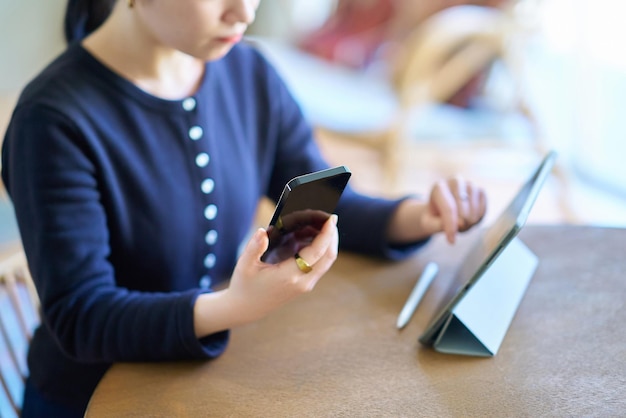 Young woman comparing tablet PC and smartphone