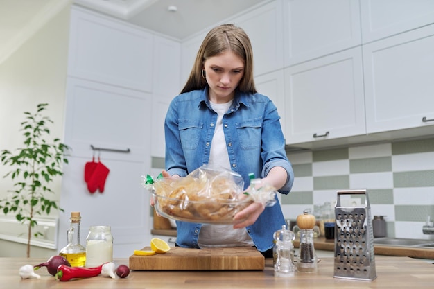 Young woman cooking baked chicken in baking sleeve with spices