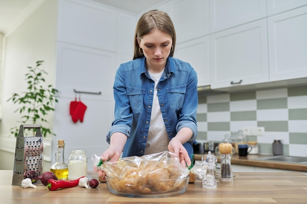 Young woman cooking baked chicken in baking sleeve with spices