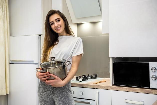 Young woman cooking  food in a pot in the kitchen.