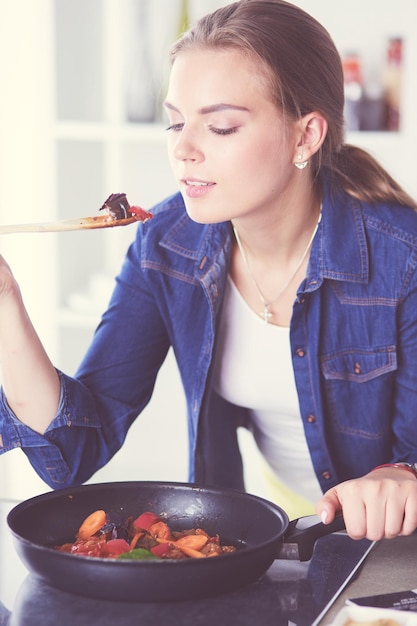 Young woman cooking healthy food holding a pan with vegetables is it healthy lifestyle cooking at ho