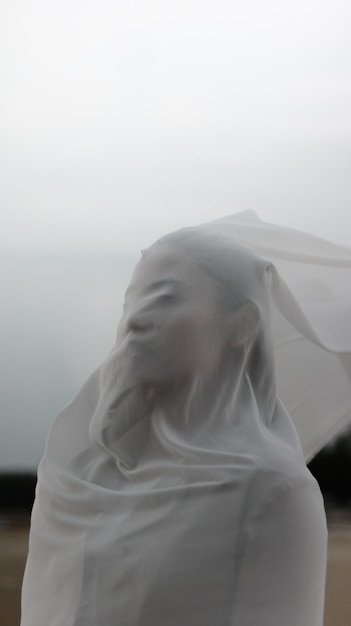 Photo young woman covering face while standing against sky