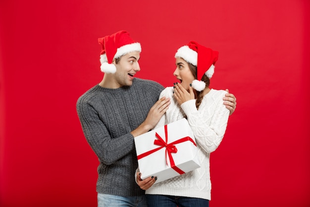 Young woman covering man's eyes with hand and giving surprise big gift