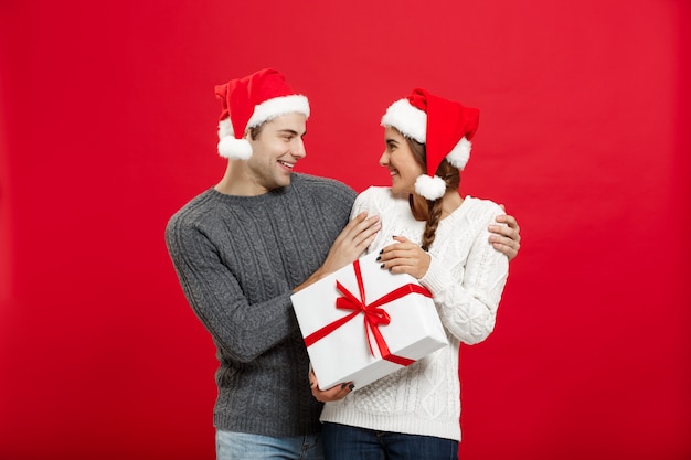 Young woman covering man's eyes with hand and giving surprise big gift