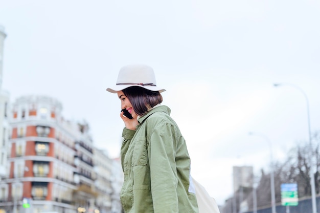 Young woman crossing the street while holding smartphone