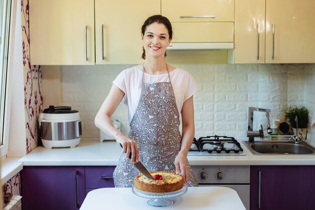 Young woman cuts a pie in the kitchen