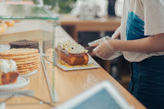 Young woman cutting cake in bakery shop