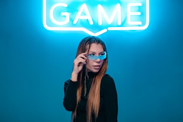 Photo young woman in cyber glasses in a neon room connecting to the game high quality photo