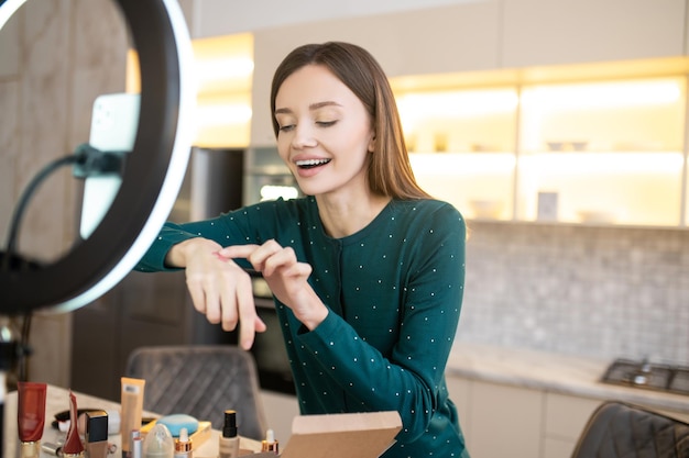 Young woman demonstrating new cosmetic products and looking involved