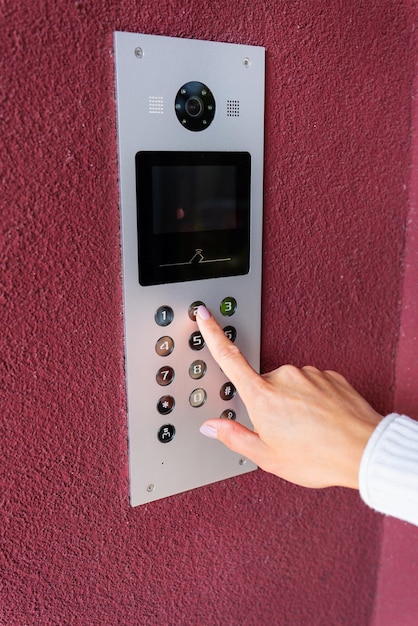 A young woman dials the apartment code on the panel of an electronic intercom Protection and safety concept