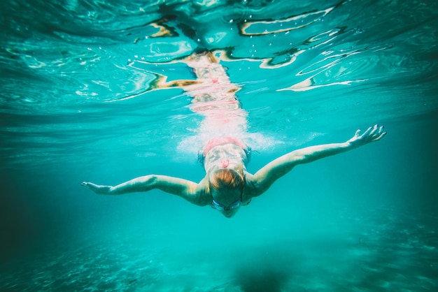 Young woman diving with mask underwater in the sea.