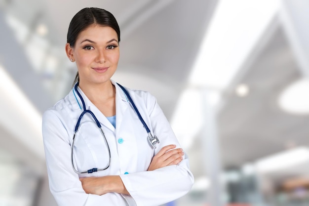 Young woman doctor holding stethoscope on background