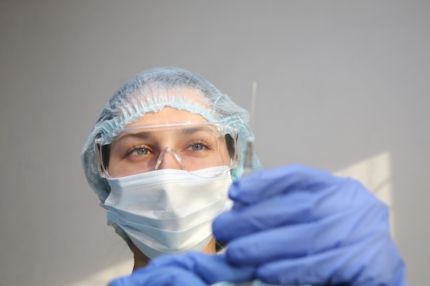 young woman doctor nurse in a protective mask with a syringe in her hand