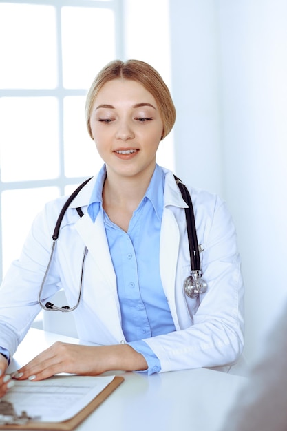 Young woman doctor and patient at medical examination at hospital office. Blue color blouse of therapist looks good. Medicine and healthcare concept.