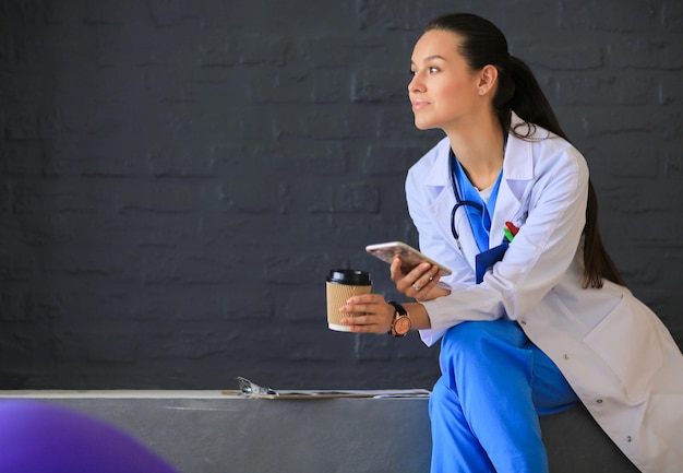 Young woman doctor sitting with your phone Woman doctors