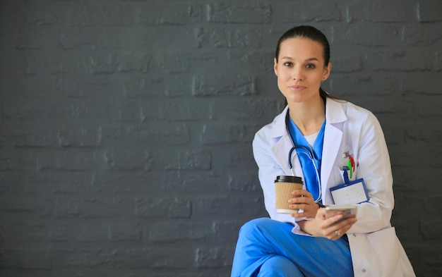 Young woman doctor sitting with your phone woman doctors