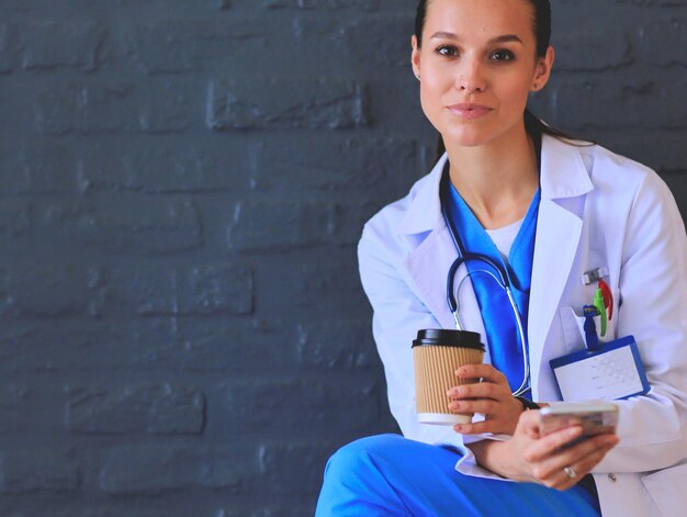 Young woman doctor sitting with your phone woman doctors