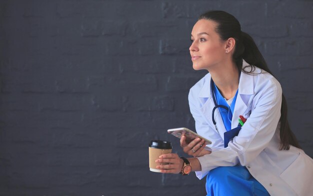 Young woman doctor sitting with your phone Woman doctors