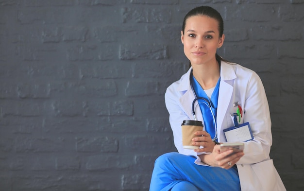 Young woman doctor sitting with your phone woman doctors