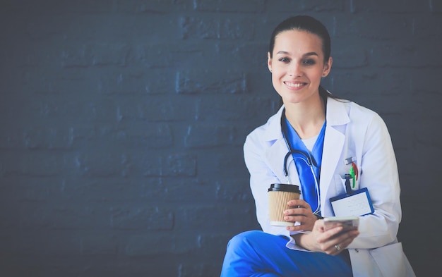 Young woman doctor sitting with your phone woman doctors