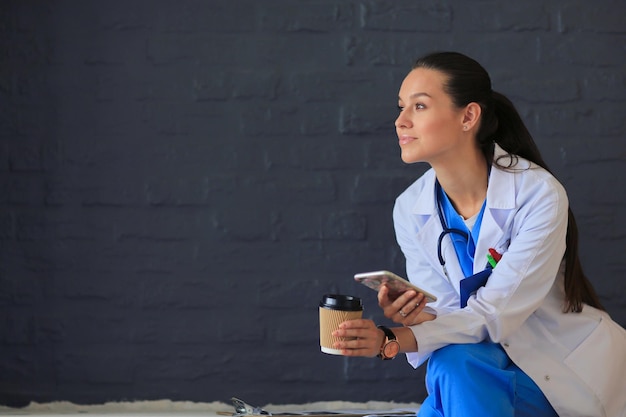 Young woman doctor sitting with your phone Woman doctors