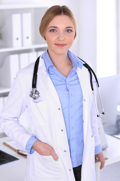 Young woman doctor at work in hospital looking at camera. Khaki colored blouse of therapist looks good. Medicine and healthcare concept.