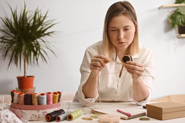 Photo a young woman does macrame needlework creates home decorations master of jewelry weaving