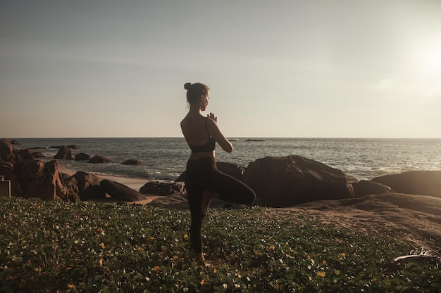 Young woman does yoga for healthy lifestyle on sea beach