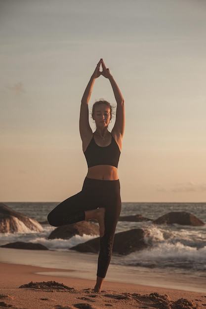 Young woman does yoga for healthy lifestyle on sea beach